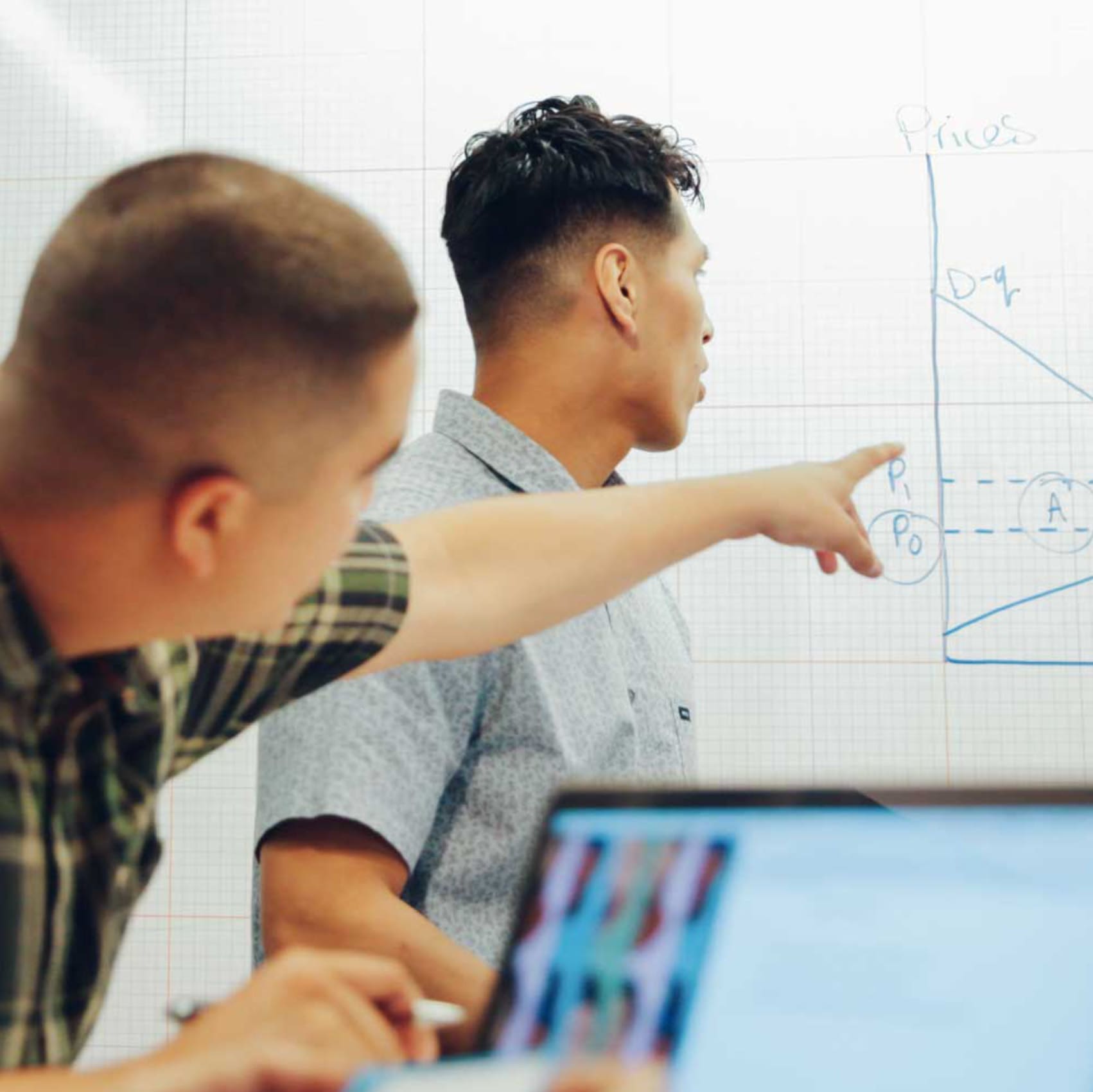 Two men pointing at a whiteboard.