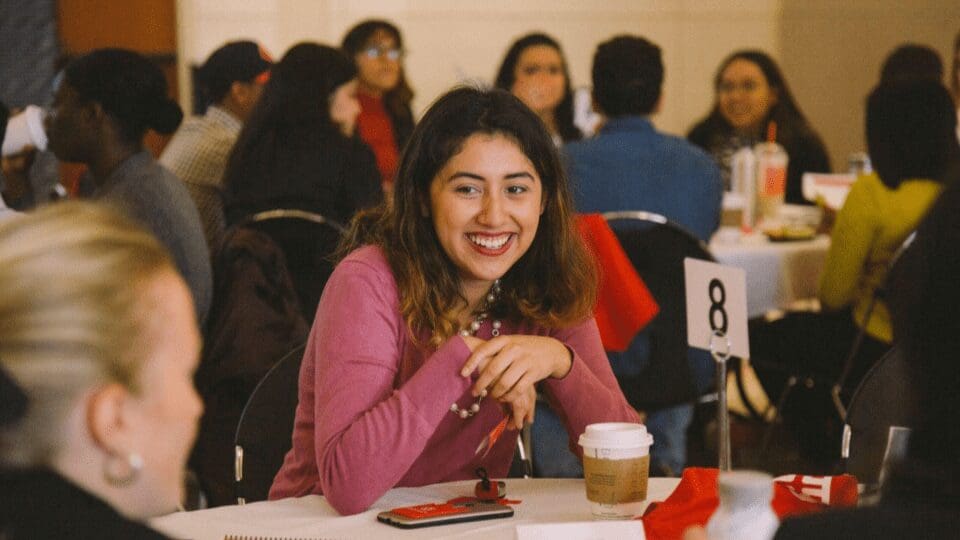 A woman smiles at a table full of people.