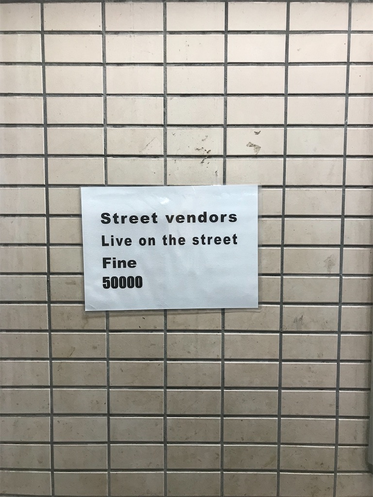 地下鉄のタイルの壁にはられた貼紙、壁は薄汚れている。