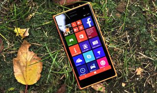 Nokia Lumia 735 in orange on grass with autumn leaves
