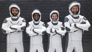 portrait of four astronauts — three men and one woman — in black and white spacesuits