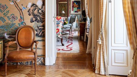 Layered entryway with wooden floors, vibrant wallpaper and leather chair