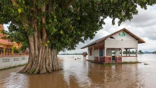 Flood waters rise to the porch of a house next to a tree in Laos