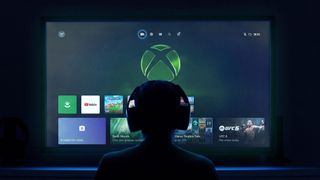 A person wearing headphones silhouetted against a TV screen displaying an Xbox interface with game icons, creating a focused gaming atmosphere.