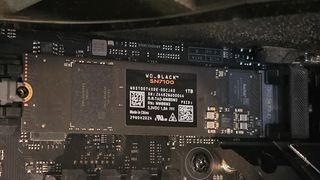 Close-up of a WD_Black SN7100 NVMe SSD installed on a motherboard. The SSD label displays its 1TB capacity and technical details.