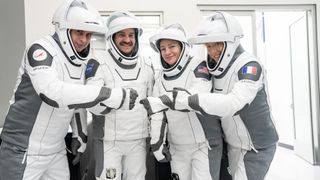 four people in white flight suits pose for a picture