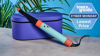Dyson AirWrap ID on a stone surface with a blue wall in the background and a Tom's Guide Cyber Monday deal badge in the top right