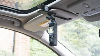 Insta360 X5 mounted to the Flexi Clip, attached to a car's sun shield