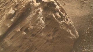 a mottled reddish-orange rock on a dusty surface of the same color