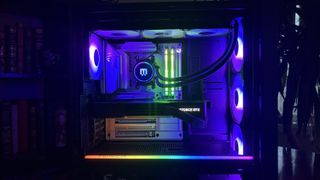 A Maingear MG-1 MK.II gaming PC with RGB lighting illuminates the interior. It features a GeForce RTX graphics card and vibrant cooling fans, creating a futuristic vibe.