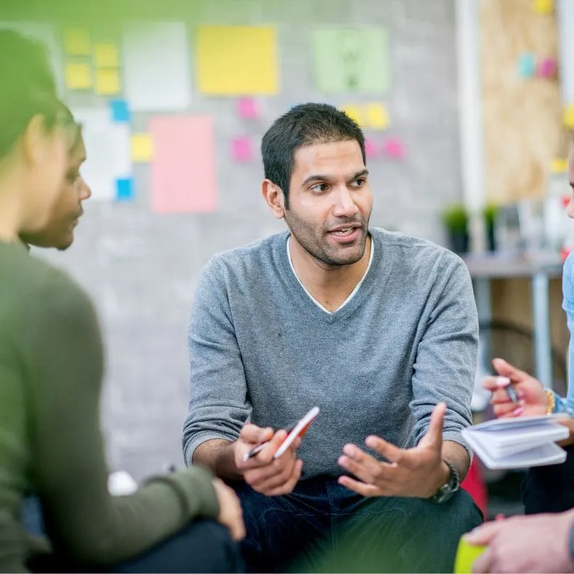 People sitting in a circle, one person talking