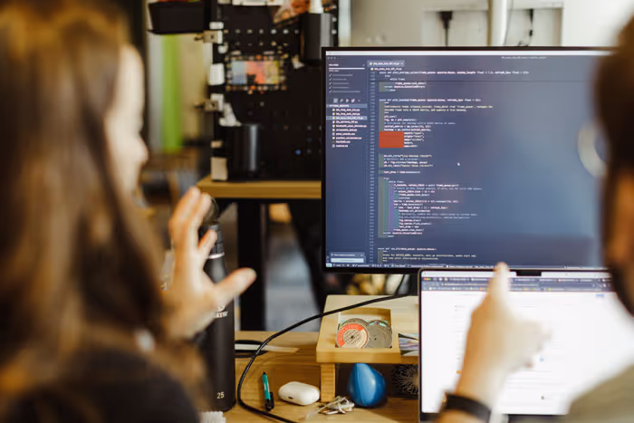 Software developers collaborating at a computer using AI-first processes