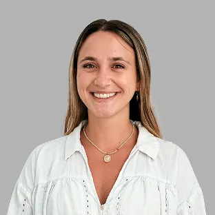 Colaboradora de Neocoast con camisa blanca y sonrisa cálida, posando frente a fondo neutro.