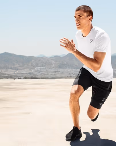 Athletic man sprinting outdoors on a clear day with mountains in the background.