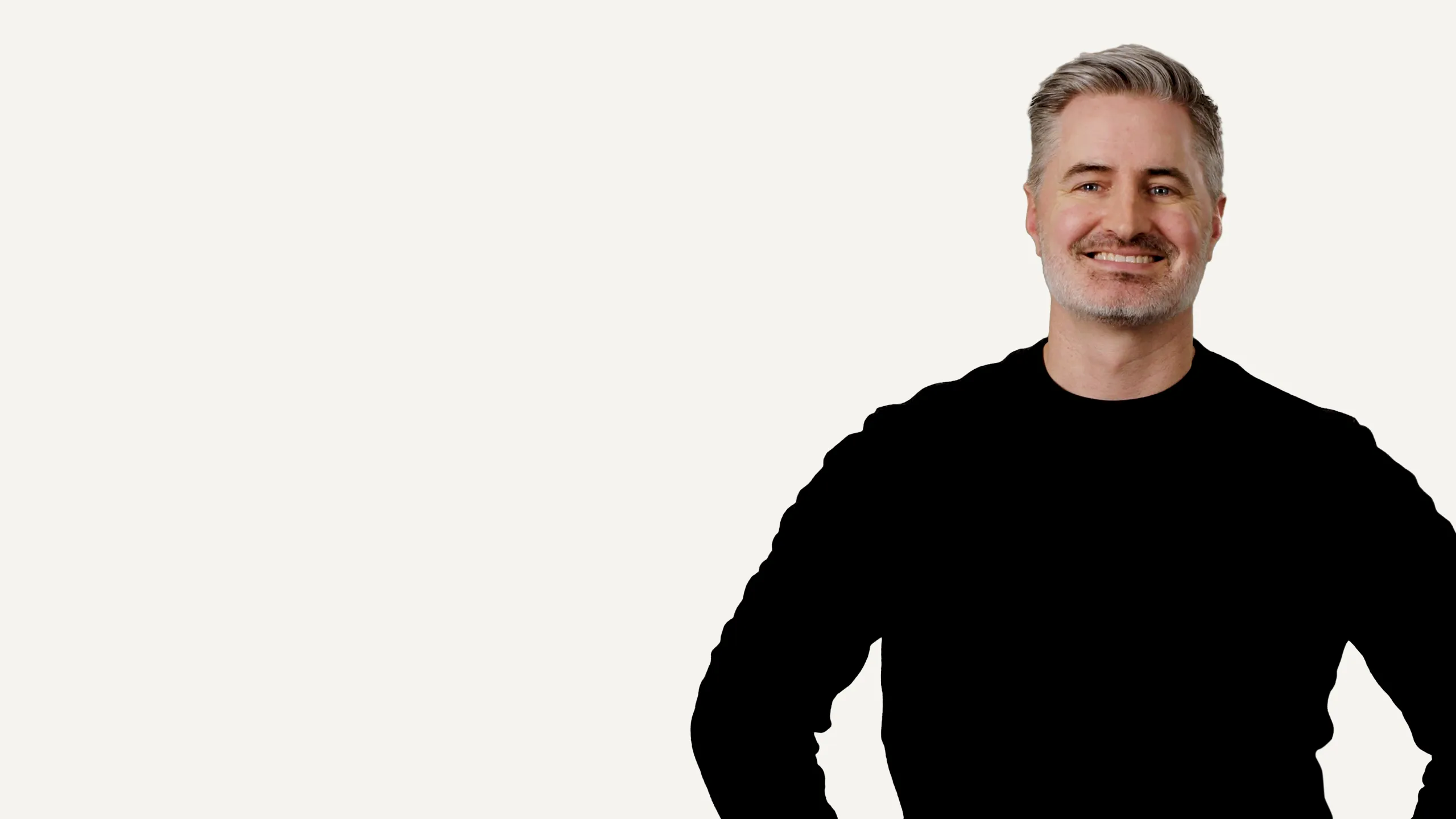 Smiling middle-aged man with grey hair wearing a black long-sleeved shirt on white background.