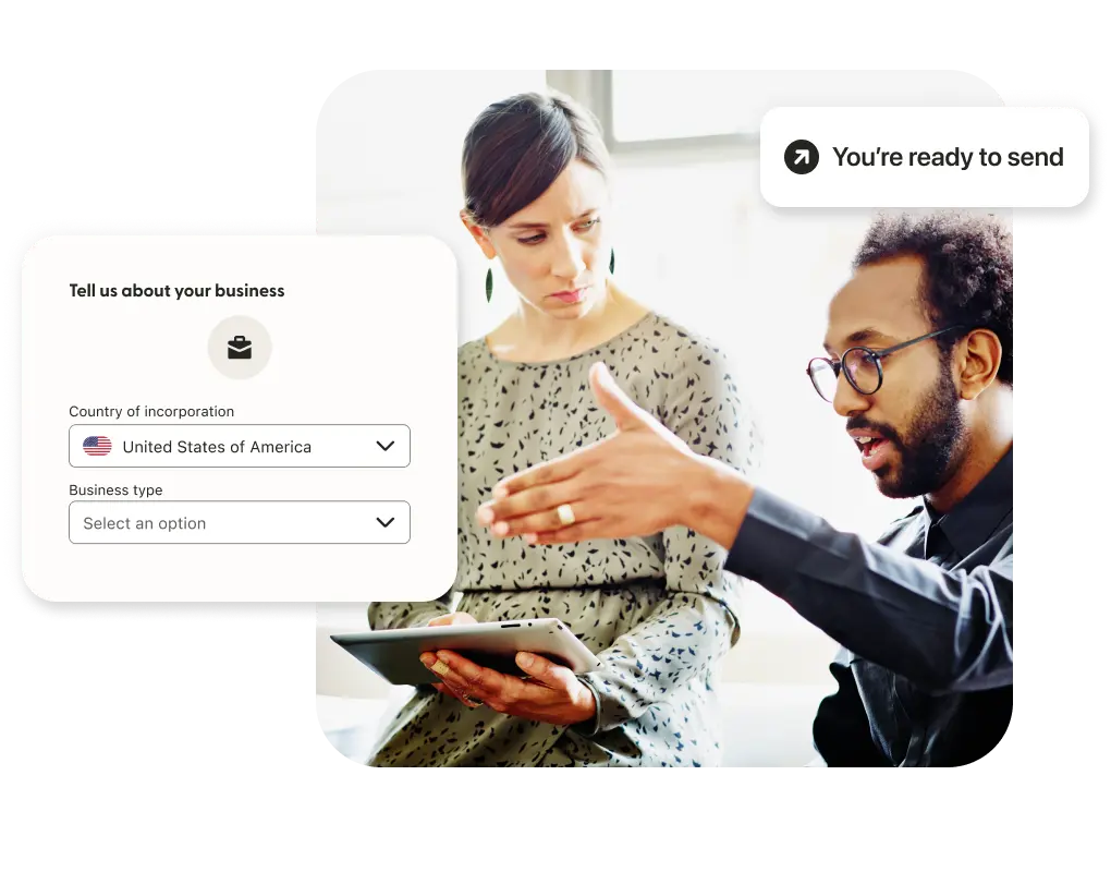 Two professionals discuss beside a simulated Remitly screen.