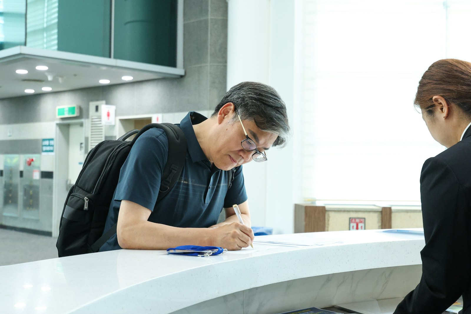 A person signing paperwork at a reception desk.