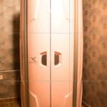 Большая белая камера футуристического вида с вертикальными панелями и двумя маленькими окнами стоит в тускло освещенной комнате с узорчатыми обоями и кафельным полом; рядом - вывеска с нашими контактами. Большая белая камера футуристического вида с вертикальными панелями и двумя маленькими окнами стоит в тускло освещенной комнате с узорчатыми обоями и кафельным полом; рядом - вывеска с нашими контактами.