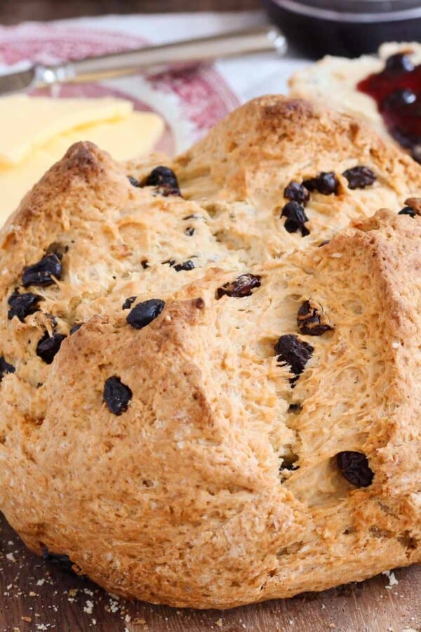 loaf of traditional Irish soda bread with butter in background.
