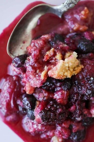 Mixed berry crumble with a silver spoon.