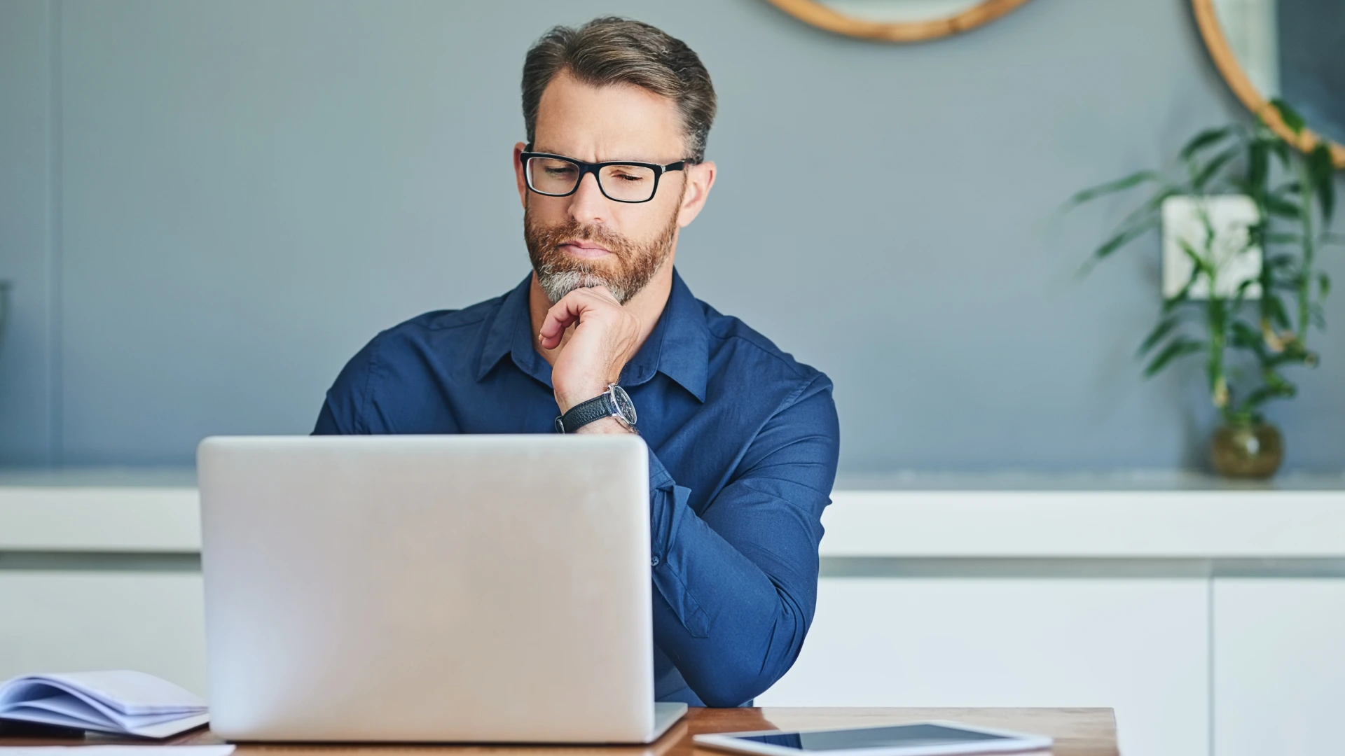 Laptop, remote working and thinking with business worker on table in home office for administration.