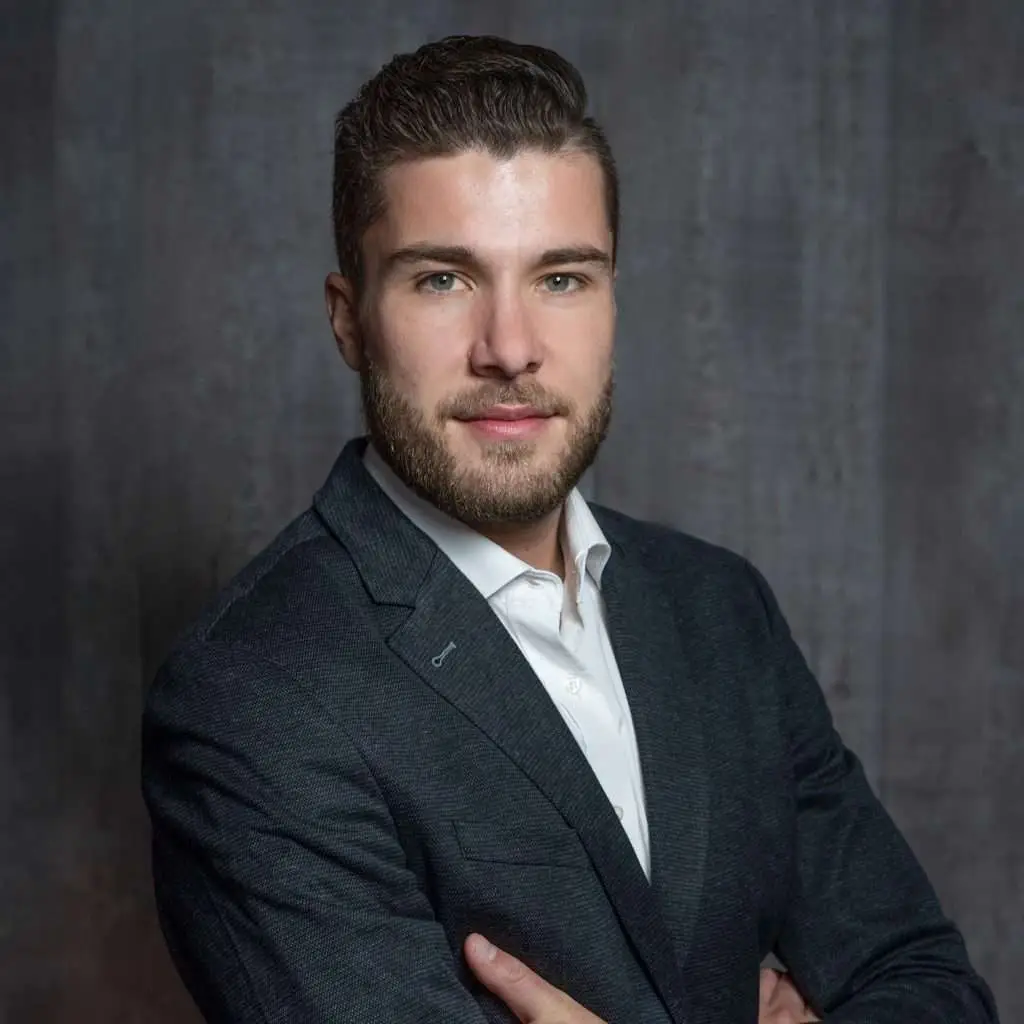 Junger Mann in Anzug vor grauem Hintergrund