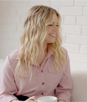 Smiling woman holding a mug, seated on a couch