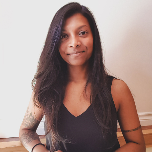 Indian woman with long hair wearing a black tank top smiles at the camera
