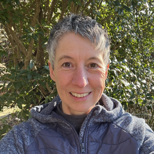 Louise Bevan smiling in front of a tree in the sunshine