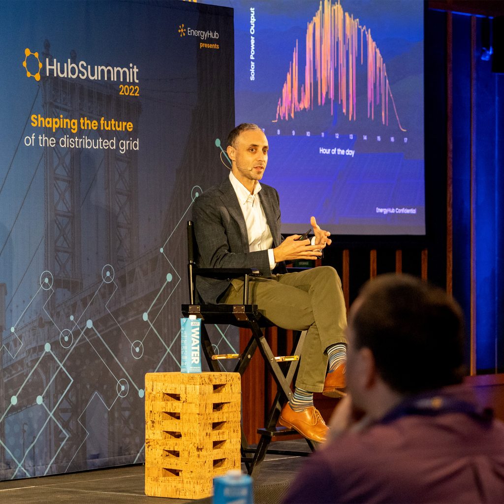 Real photograph from HubSummit 2022 by EnergyHub showing keynote speaker on stage with data visualisation screen, used to illustrate presentation and PowerPoint design services.