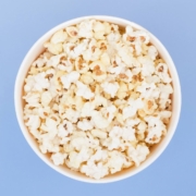 Popcorn in a paper cup is isolated on a pastel blue background, a view from above. Flat lay. Copyspace. Background. Cinema Concept