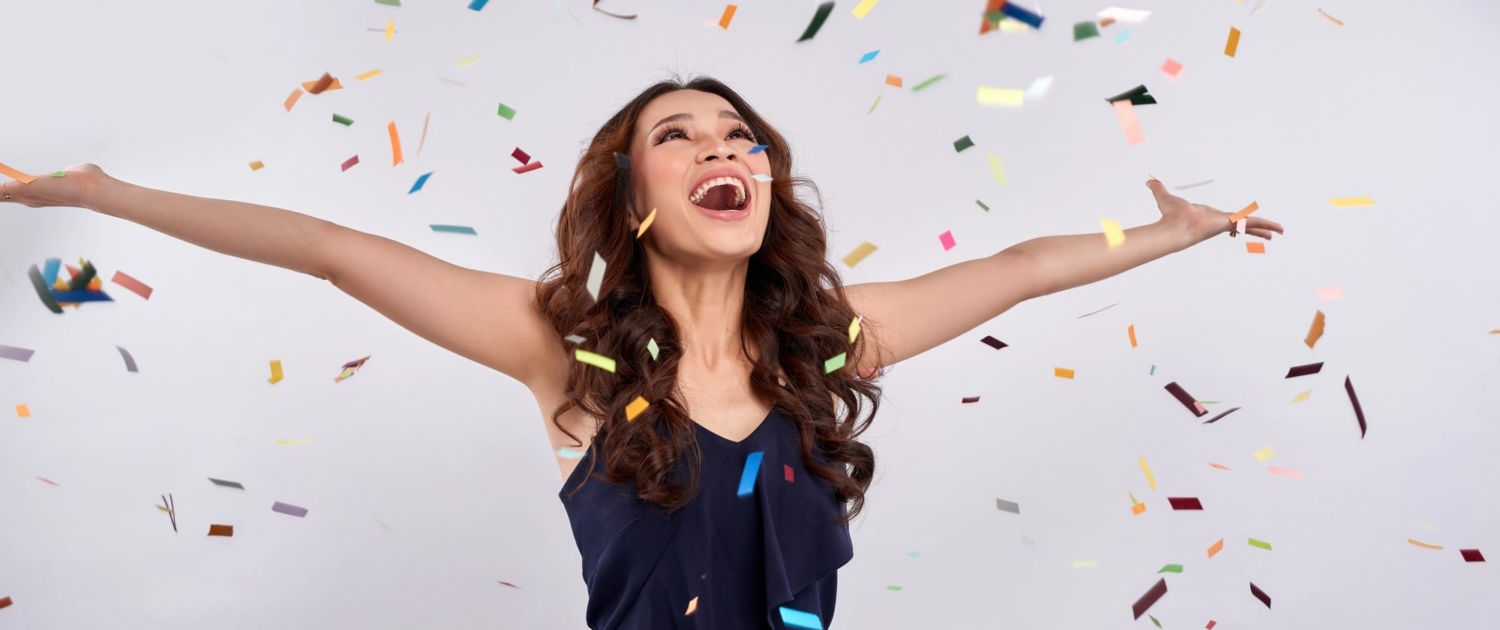 Beautiful happy woman at celebration party with confetti falling everywhere on her. Birthday or New Year eve celebrating concept