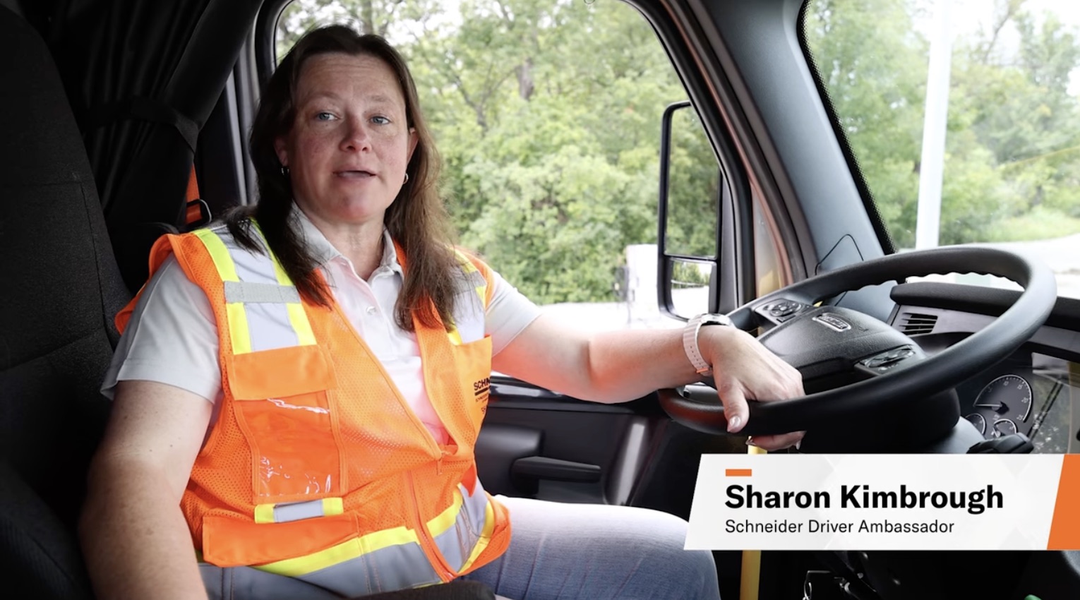 A photo of a female truck driver named Sharon Kimbrough at the wheel of a semi-truck.