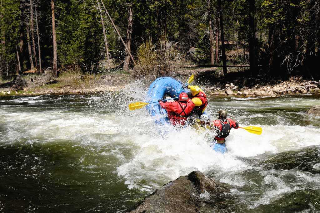 Two people on a raft hitting some turbulent waters.
