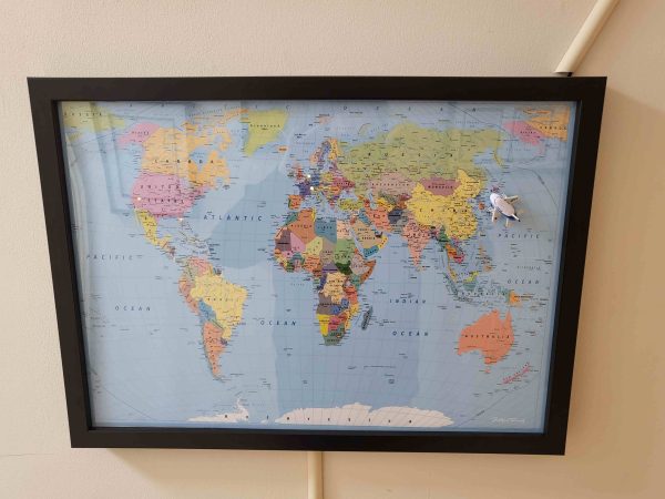 A world map with a small magetic plane sitting on Japan