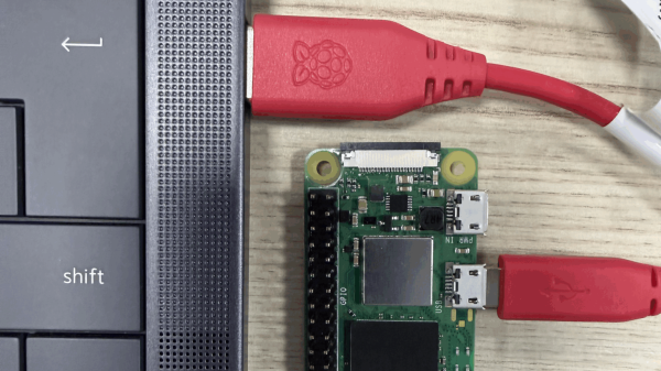The edge of a laptop is shown with a USB cable plugged into it. the other end of the cable is plugged into a Raspberry Pi Zero.