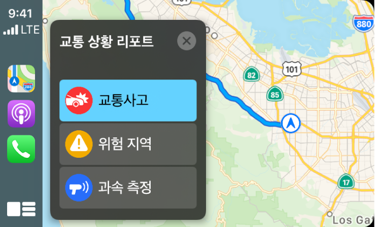 왼쪽에는 지도, 팟캐스트, 전화 아이콘, 오른쪽에는 교통 사고, 위험 지역 또는 과속 측정을 리포트하는 현 위치의 지도를 표시하는 CarPlay.
