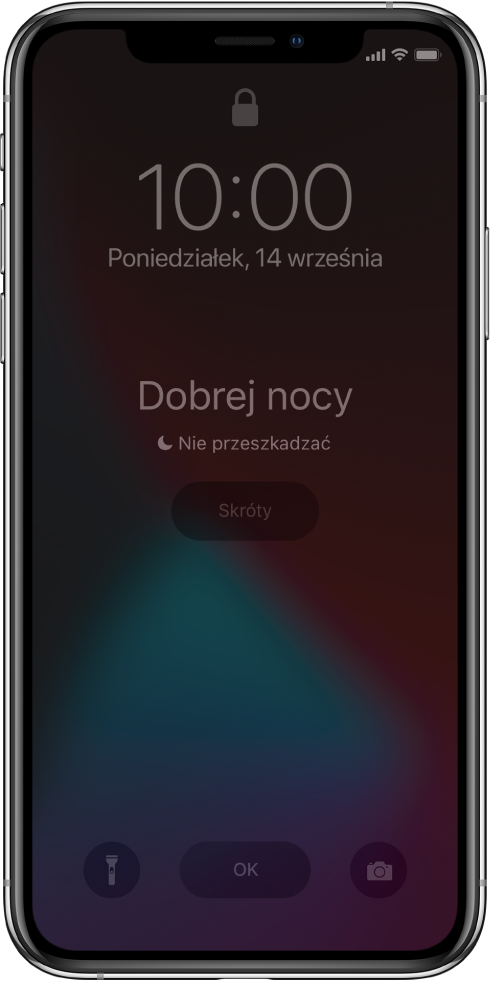 Ekran iPhone’a z wyświetlonym komunikatem Dobrej nocy oraz Tryb Nie przeszkadzać jest włączony. Poniżej widoczny jest przycisk Skróty. Na dole ekranu, od lewej, znajdują się przyciski: Latarka, OK oraz Aparat.