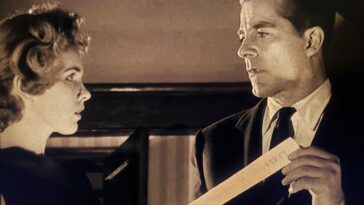 Performers Peggy Cummins and Dana Andrews reading the parchment slip containing the titular curse in Curse of the Demon