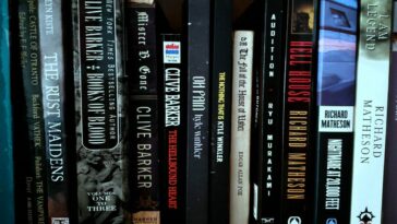 Books on shelf stacked tightly side by side, each from the horror genre.