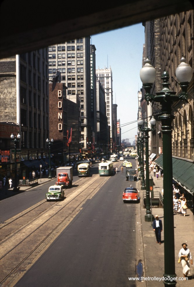On July 4, 1953, we are looking north from the stairway to the CTA's "L" station at State and Van Buren. Streetcars are still running on State Street, via tracks laid in concrete about ten years before when the State Street subway was built. The nearby subway entrances are in their original configuration. State did not get those "preying mantis" street lights until 1959.