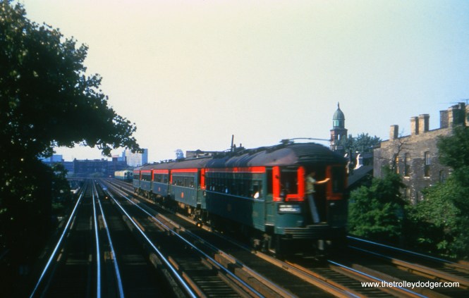 A five-car CNS&M train on Chicago's north side. In the days before air conditioning became standard on rapid transit cars, a rider holds the door open on a hot day to take advantage of the breeze.