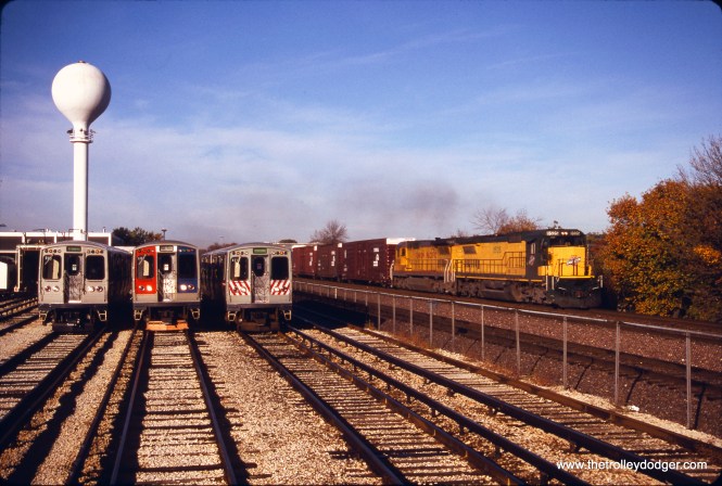 On October 20, 1996, a C&NW freight train passes some CTA 2400s (2457, 2512, and 2410) in the Green Line yard in Forest Park. (Bruce C. Nelson Photo)