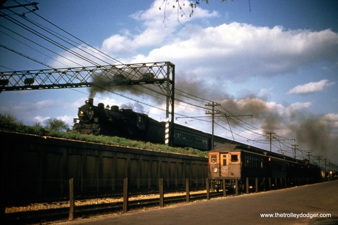 The date of this picture is not known, but it must have been in the early 1950s. We see a Chicago & North Western commuter train (aka a "Scoot") at left on an embankment, while an eastbound CTA train is on the ground level portion of the Lake Street "L". Perhaps a more exact location can be determined by the signal tower shown in the photo. I think the woods were off of Lake by the end of 1954, and steam only lasted a couple more years on the C&NW. Now both Metra commuter trains and CTA's Green Line trains share this embankment. (William Shapotkin Collection)