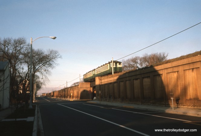 An eastbound two-car Lake Street "L" train heads east on November 24, 1963, after having left the terminal at Harlem Avenue. South Boulevard has been resurfaced, and parking spaces (with meters) added where the tracks used to be. (William C. Hoffman Photo)