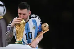 Lionel Messi embrassant le trophée de la Coupe du Monde gagnée par l'Argentine au Qatar en 2022.
