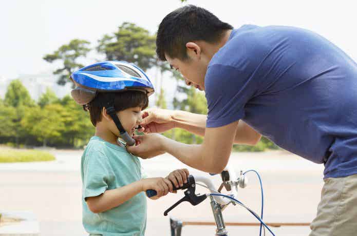 子どもにヘルメットをかぶせる大人