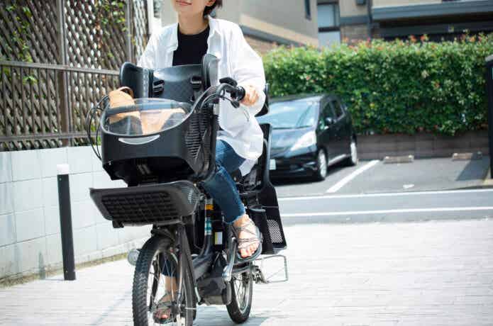 子乗せ電動自転車で走る女性