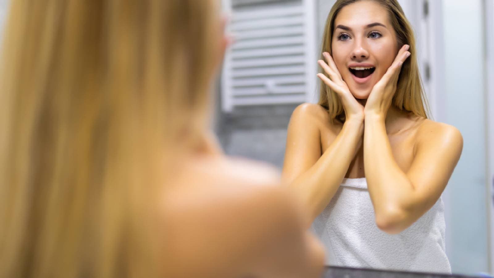 A woman smiling at herself in the mirror.