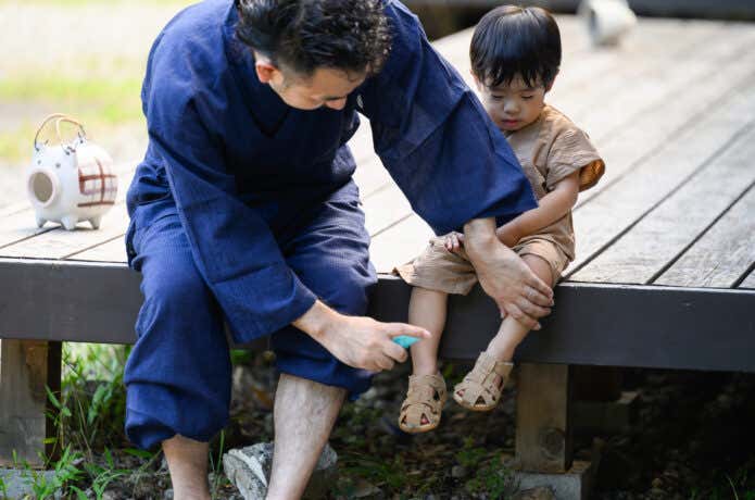 子供の脚に虫除けをかける親